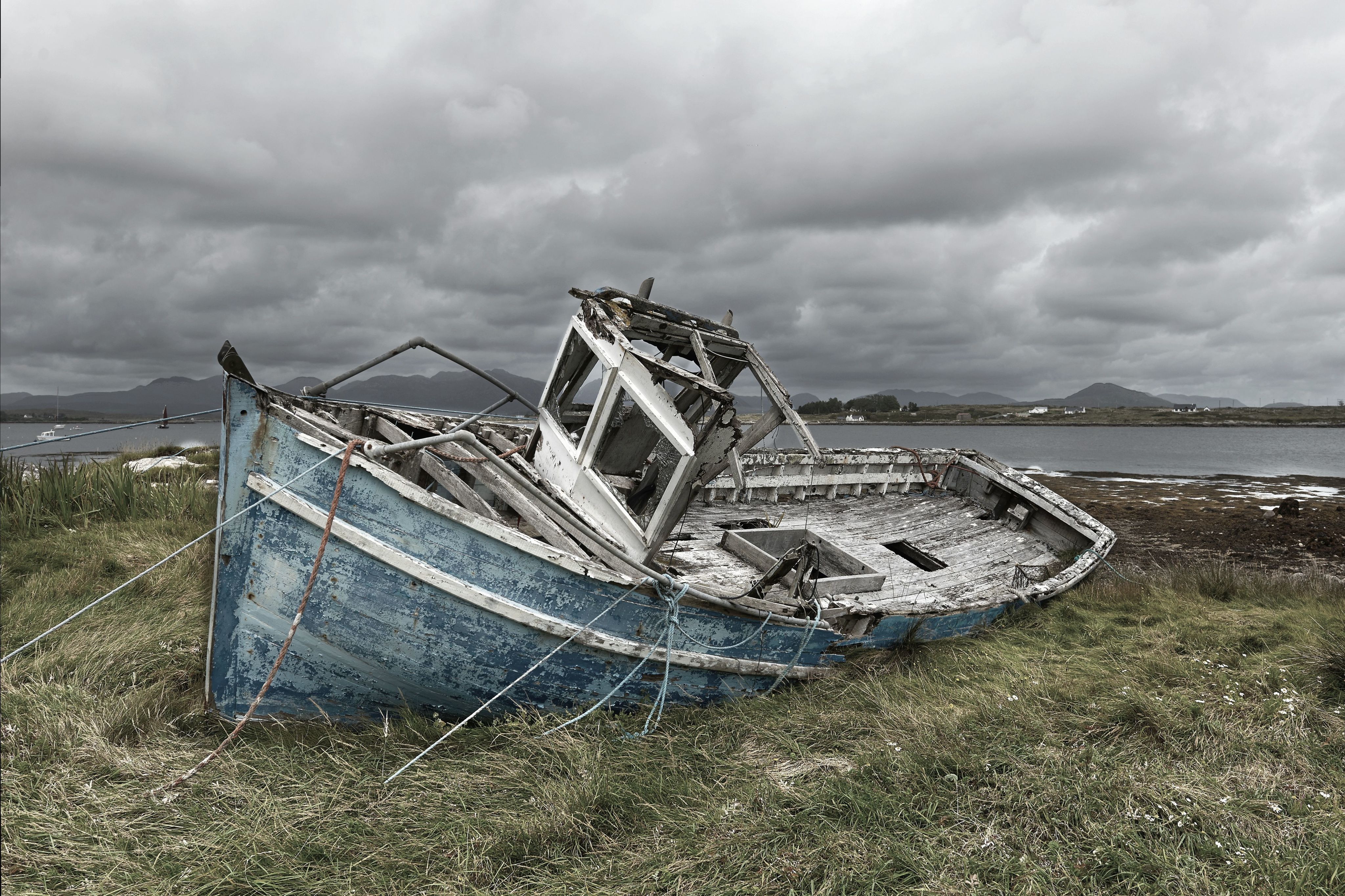 Old abandoned boat on land by the ocean.