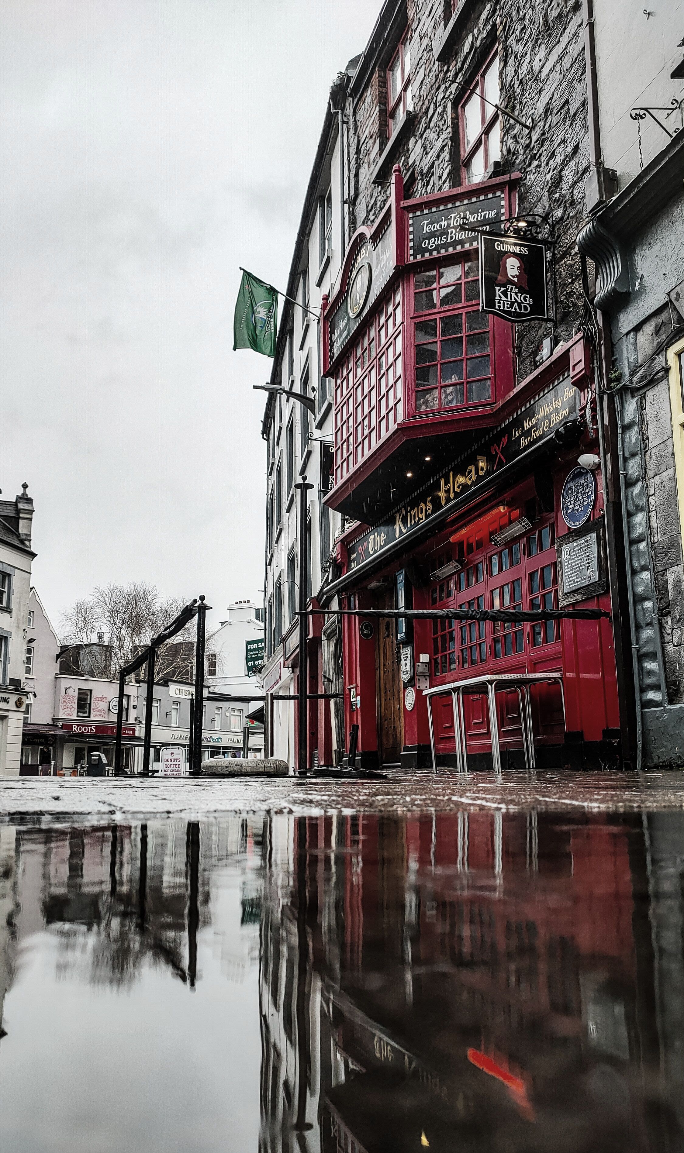 An outside view of the Kings Head Pub. The pub painted red while the sky is cloudy.